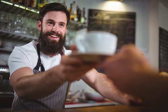 Waiter serving a cup of coffee to customer in café